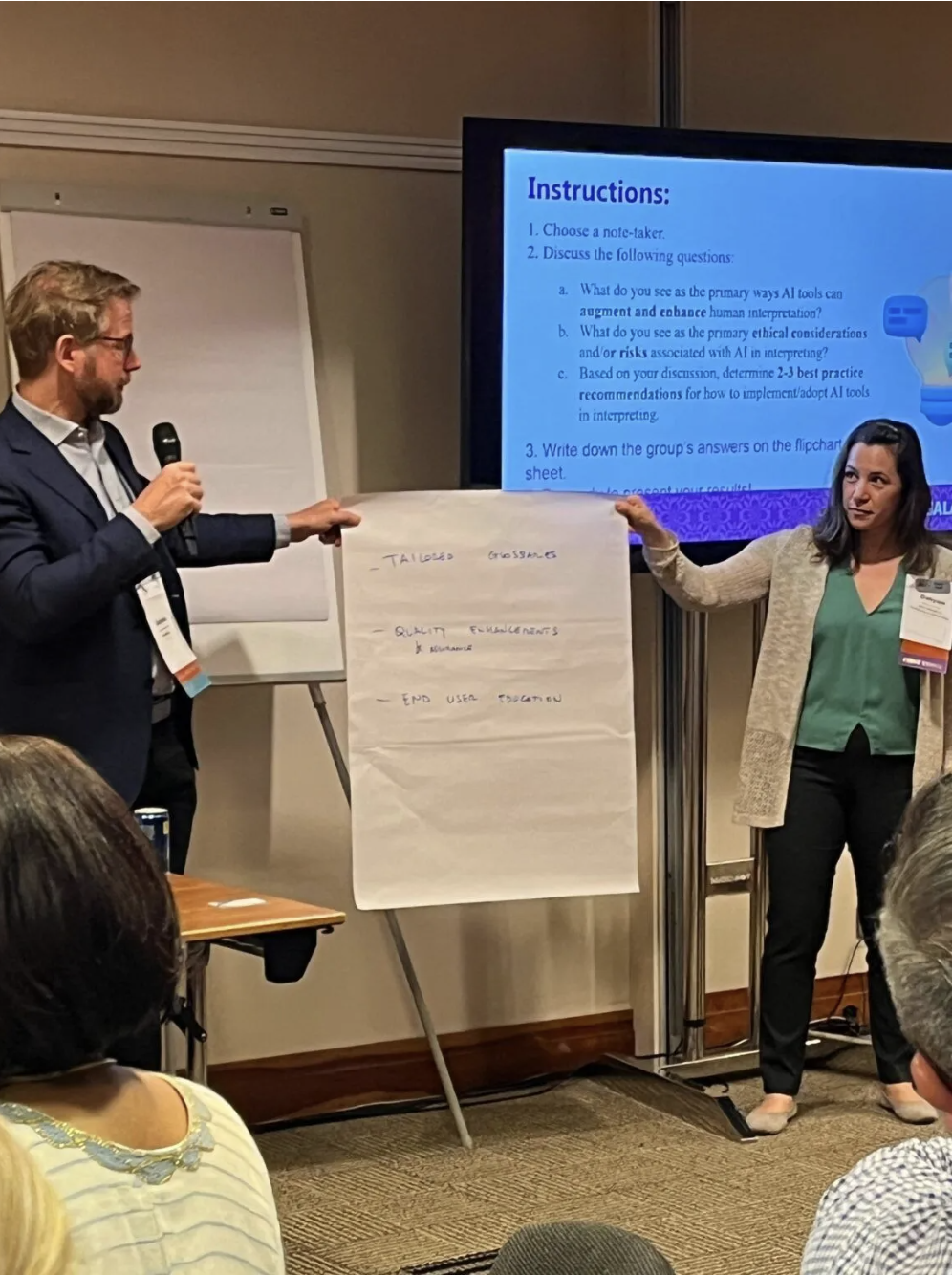 two people standing, each one holding a side of a poster